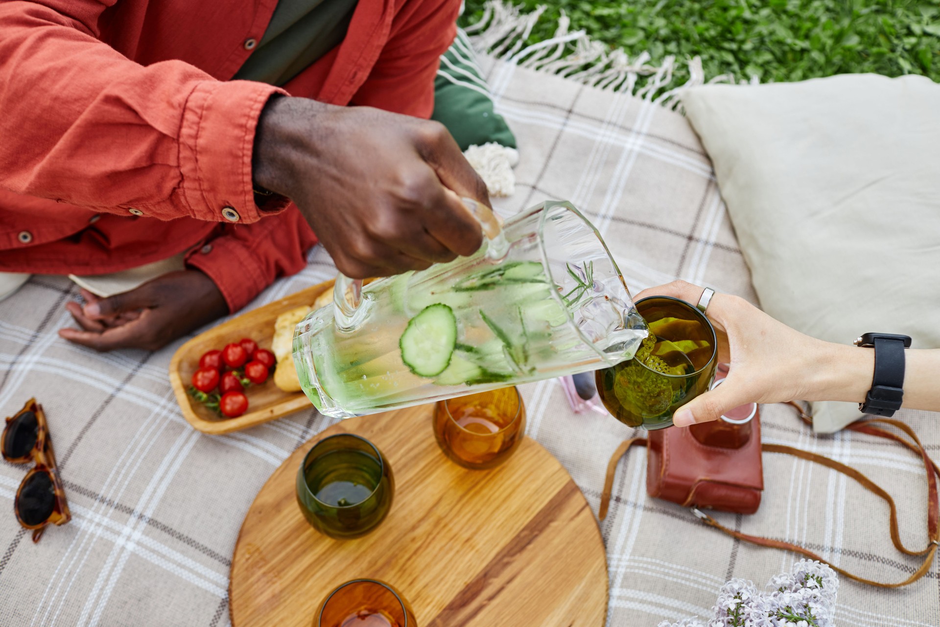 Pouring Refreshing Cucumber Water During Picnic Gathering